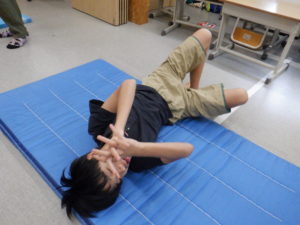 マットの上で笑顔で横に転がる利用者様