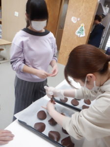 生地をオーブン皿に乗せる職員と、それを見守る利用者様