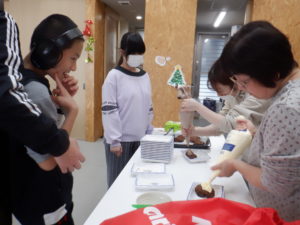 クッキーシューにトッピングする職員と、見守る利用者様たち