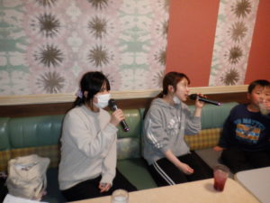 一緒に歌う利用者様と職員、それを聴く利用者様